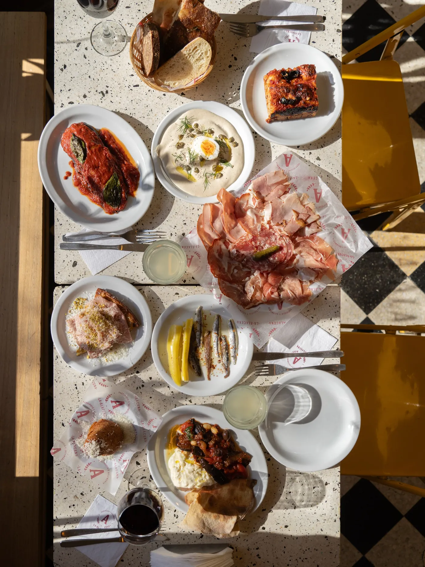 Mesa de granito de La Alacena vista desde arriba, con antipasti, salumi, pan y vino