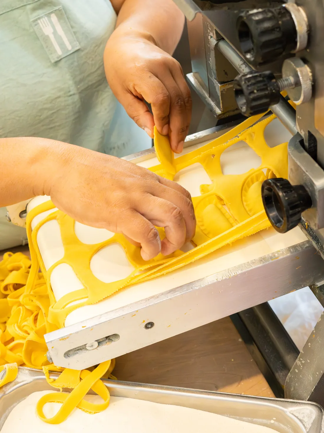 Lámina de pasta amarilla saliendo de la laminadora