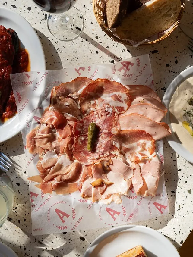 Piatto di salumi sobre papel de La Alacena